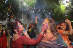 Professors engaging in Holi fun with students in a vibrant atmosphere.