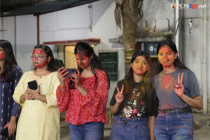 A cheerful group of students enjoying Holi festivities with music and dance.