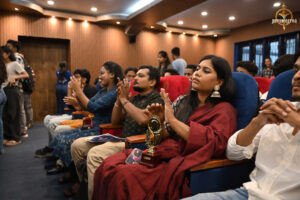 Bid to Win participants applauding while watching the stage during the financial simulation event at RCM.