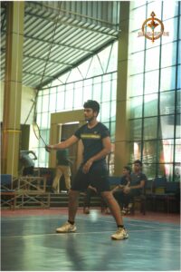 Student smashing a shuttlecock during an intense badminton match at Brahmastra 2025, RCM Bhubaneswar.
