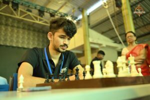 “Two college students A focused student in glasses makes a chess move while seated at a chessboard during the Brahmastra 2025 Kurukshetra college fest.