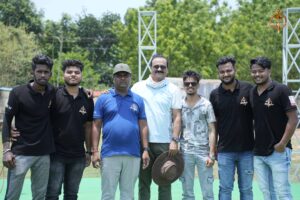 Two college cricket team captains and the umpire standing together at the pitch’s center before the toss at Ranbhoomi (Brahmastra 2025)."