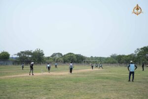 Cricket match in progress during Ranbhoomi at Brahmastra 2025, with players actively fielding on a grassy pitch under daylight.
