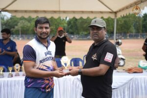 Faculty member presenting a trophy to a student receiving an award on stage at Brahmastra 2025.