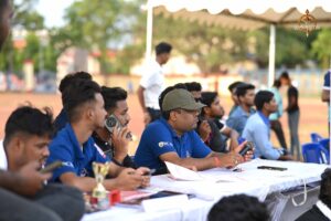 cricket team in jerseys intently watching a Ranbhoomi match from the sidelines at Brahmastra 2025.