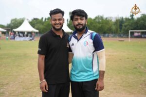 Two team captains at the toss during Ranbhoomi cricket match at Brahmastra 2025, standing on the pitch in team jerseys.