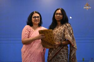 Faculty presenting a token of appreciation to a woman entrepreneur at college festival Brahmastra 2025 event.