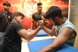 Two men engaged in an intense arm wrestling match during the Kurukshetra Brahmastra 2025 event at Regional College of Management, Bhubaneswar.