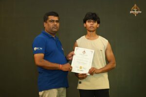 Certificate distribution ceremony during Brahmastra 2025 Kurukshetra Arm Wrestling event at RCM Bhubaneswar with participants and faculty on stage.