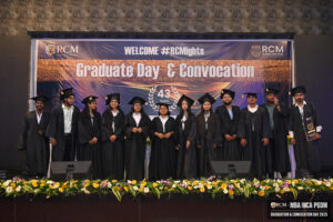 Graduates in caps and gowns on stage at RCM Global BSchool's 43rd Graduate Day & Convocation.
