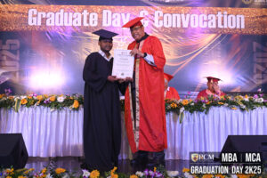 Graduate receives certificate on stage from person in red gown during RCM Graduation Day 2K25.