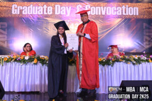 Graduate receives diploma from official in regalia at RCM Graduation Day 2K25 ceremony.