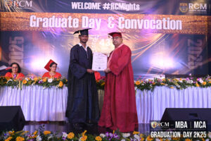 Graduation event with a graduate receiving a certificate on stage, 2025 backdrop visible.