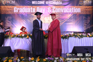 Graduate receives certificate from faculty member at RCM Global B School's 2025 ceremony.