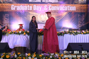 Graduate in black gown receives certificate from person in red at RCM Global School event.