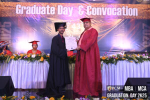 Graduation ceremony with individuals in caps and gowns; banner reads "Graduate Day & Convocation".