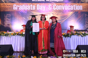 Graduate receiving certificate on stage at "Graduate Day & Convocation," floral decor present.