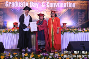 Graduate in cap and gown receiving certificate on stage at a convocation ceremony.
