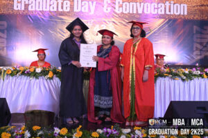 Graduate in cap and gown with certificate, flanked by faculty in red robes at a ceremony.