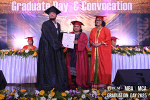 Graduation ceremony with a graduate in black gown receiving a certificate from officials.