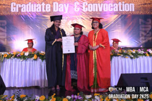 Graduate receiving certificate on stage at RCM Graduation Day 2K25 for MBA/MCA program.