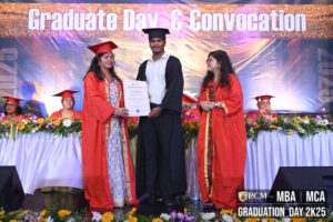 Graduation ceremony with graduate receiving diploma on stage, banner reads "Graduate Day & Convocation".