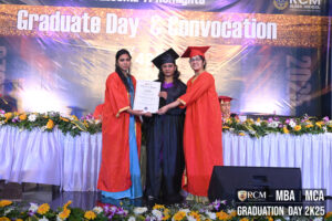 Three people on stage, RCM Global School Graduation Day 2025, with certificate and floral decor.
