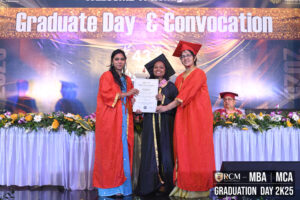Graduation ceremony with individuals in gowns holding a certificate, banner reads "Graduate Day & Convocation."