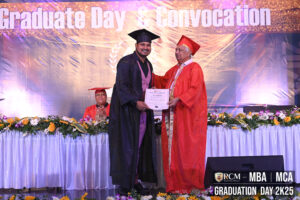 Graduate receives certificate on stage during convocation; backdrop reads "Graduate Day & Convocation".