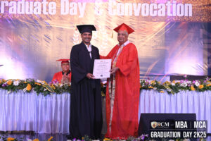 individual in black gown receives certificate from person in orange robe.