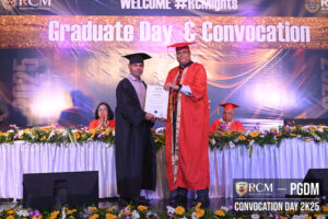 Graduate in cap and gown receives certificate from official in orange robe at convocation ceremony.
