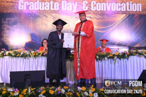 Graduate in cap and gown receives certificate from faculty in red regalia at convocation 2025.