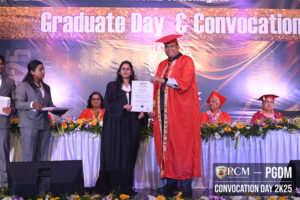 Woman receives certificate from man in academic gown during convocation ceremony on stage.