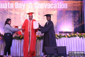 person in black gown receives certificate from individual in red robe.