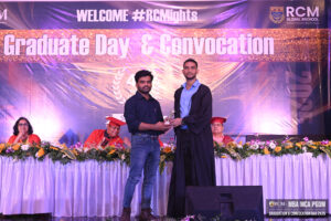 Graduate in black gown receives trophy at RCM Global B-School's convocation event.