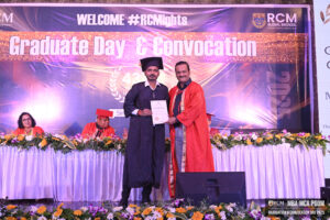 Graduation ceremony at RCM Global B School with student receiving certificate on stage.
