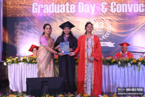 Graduate on stage receiving a certificate during a ceremony with "Graduate Day & Convocation" backdrop.