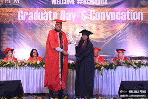 Graduate in black gown receives certificate from person in red gown at convocation ceremony.