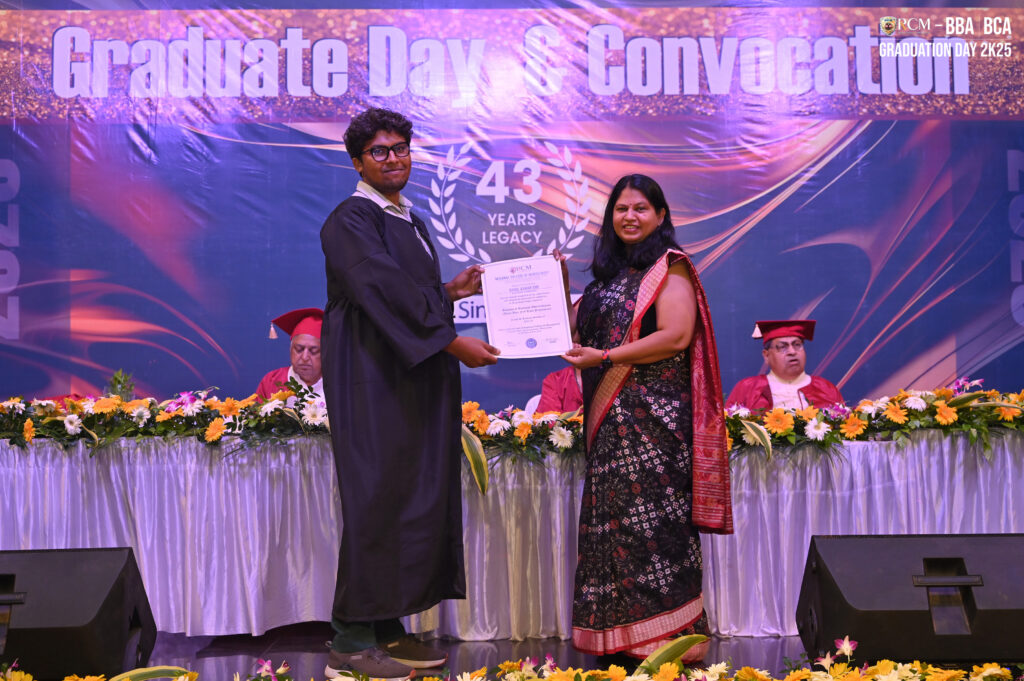 Graduate receiving certificate from a woman during Graduation Day, "43 Years Legacy" backdrop.