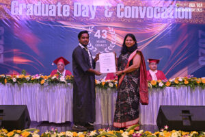 Graduate receiving certificate at RCM event, with backdrop "Graduate Day & Convocation."