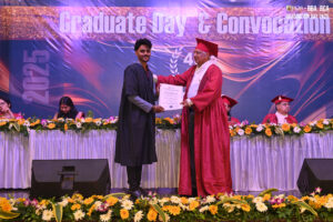 Graduation ceremony with certificate presentation, floral decorations, and "Graduation Day 2025" backdrop.