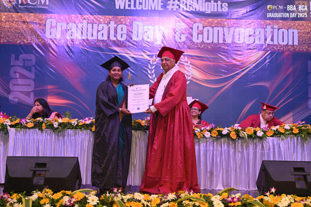 Graduation ceremony with two people exchanging a certificate on a decorated stage.