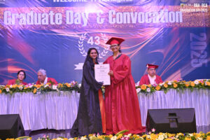 Graduate receives certificate on stage during convocation, celebrating 43 years of the college.