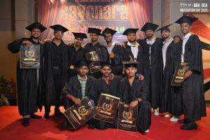 Graduates in black caps and gowns holding certificates on red carpet, "Sayonara Night" backdrop.