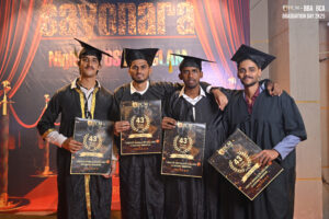 Graduates in caps and gowns holding certificates at RCM's 2K25 BBA and BCA graduation event.