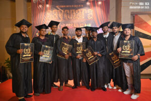 Graduates in caps and gowns with certificates on a red carpet at a BBA and BCA event.