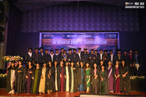 Graduates posing on stage in gowns and caps at RCM Global School’s convocation ceremony.