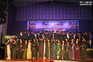 Graduates in gowns and caps on stage with "Graduate Day & Convocation" banner in background.