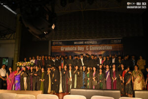 Graduates on stage in gowns and caps during indoor Graduation Day & Convocation ceremony.