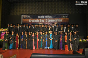 Graduates in caps and gowns pose on stage at RCM Global School's convocation ceremony.